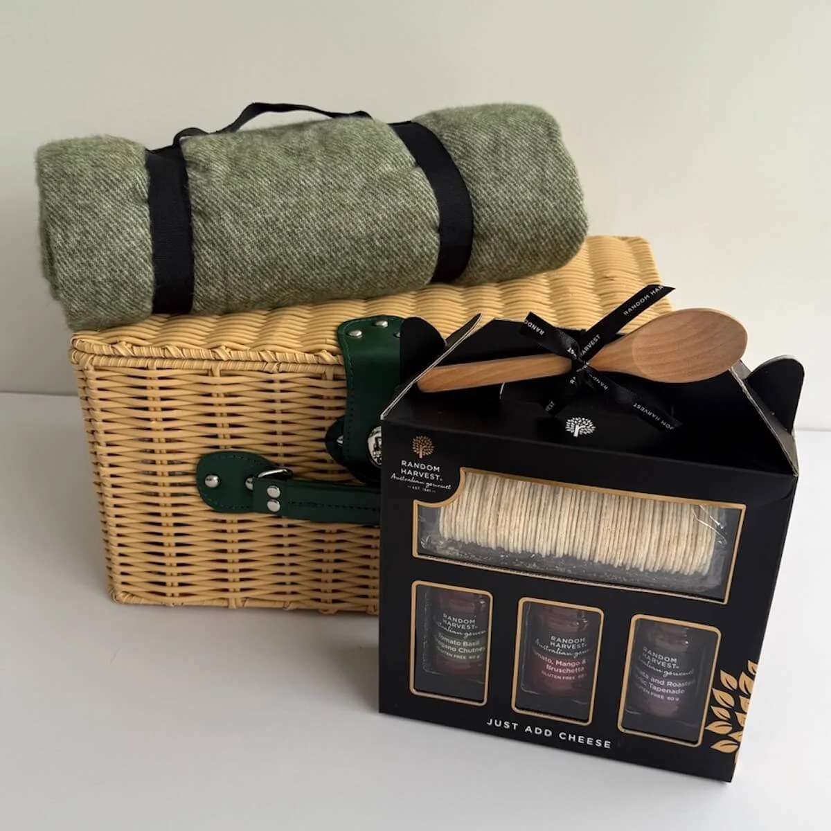 Picnic hamper closed with a blanket and pack with crackers, spreader and assorted sauces.