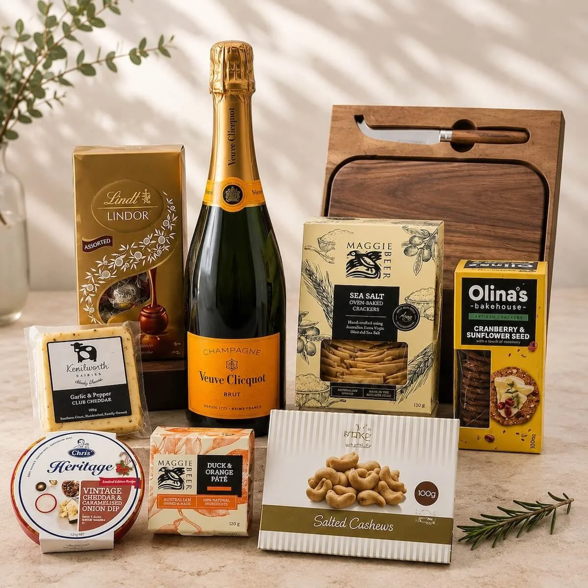 Veuve champagne hamper itemswith a wooden cheese board and knife. Includes savoury a sweet items to create a stunning gift.