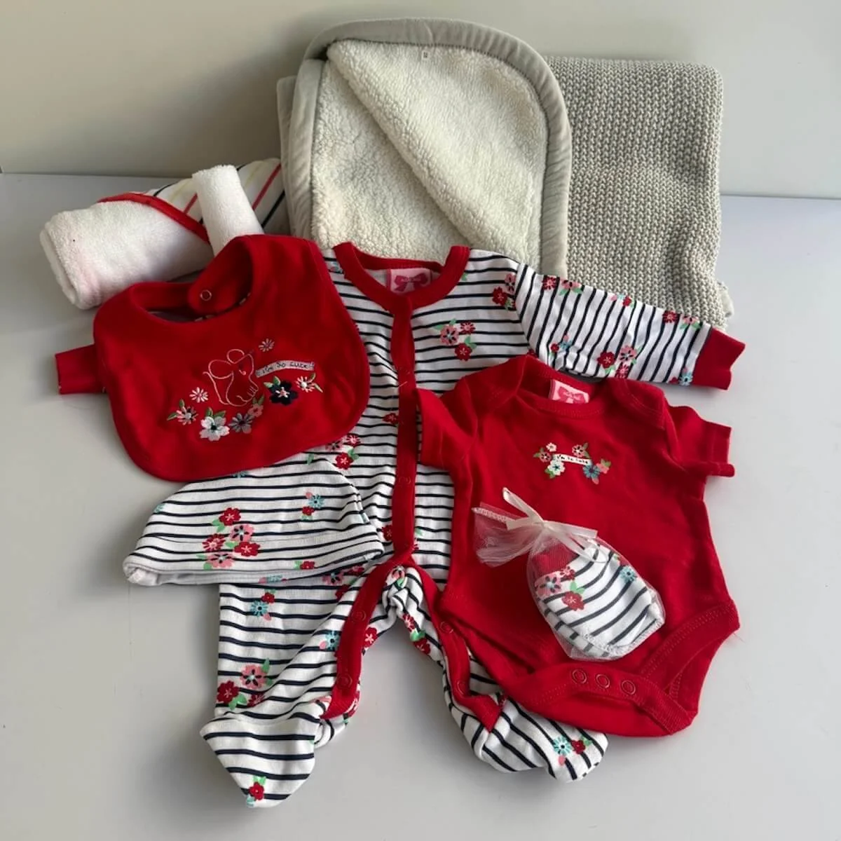 5 peice clothing set which is red with a small flower theme newborn size that is inlcuded in the Pretty Petals gift bag for a baby.