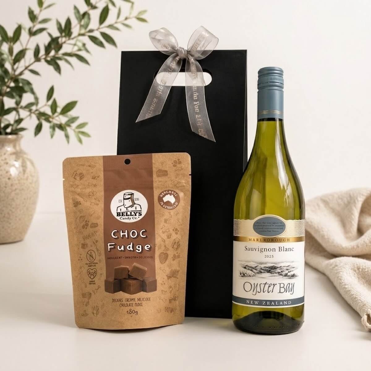 Black gift bag with a bottle of wine and Kelly’s chocolate fudge, an elegant wine and sweet treat gift perfect for celebrations and thank yous.