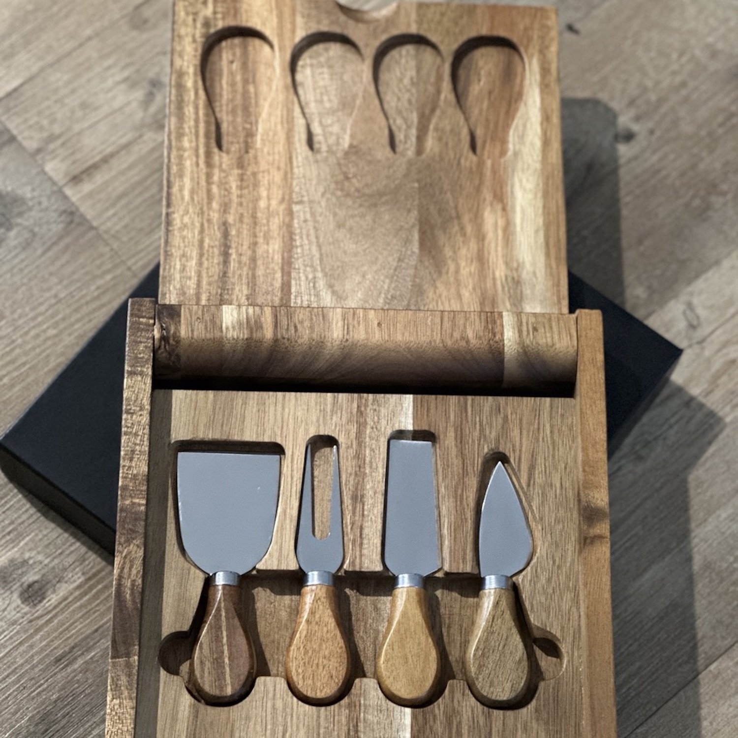 A wooden board with a hinged lid and 4 cheese knifes inside.