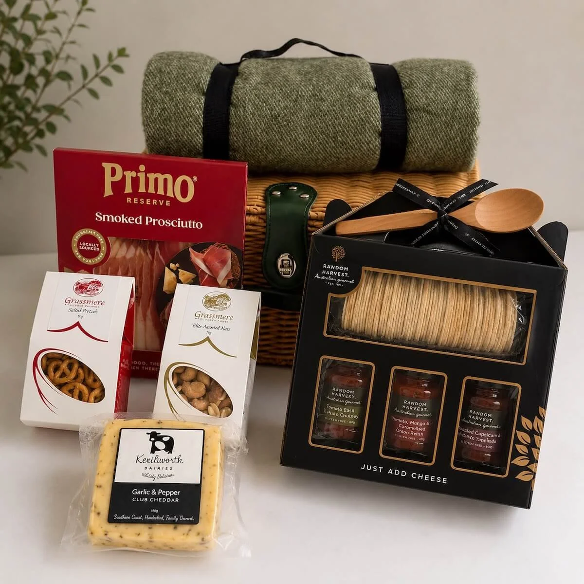 Gourmet picnic hamper for four with plastic wicker basket, picnic blanket, plates, cutlery, cups, cheese, prosciutto, nuts, chutneys, and crackers