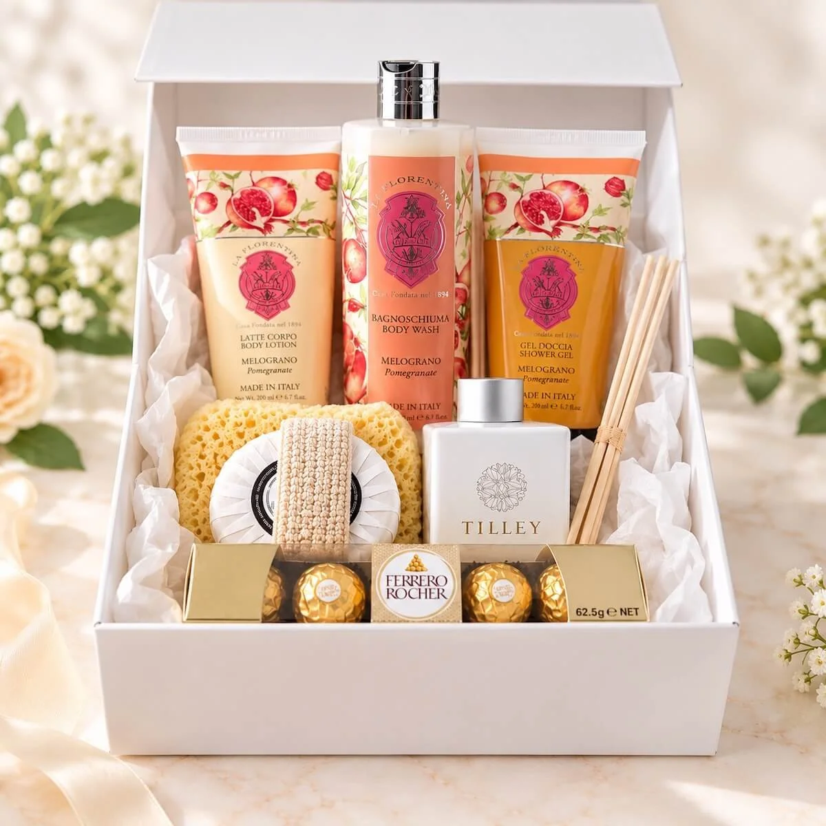 Luxury pamper gift hamper with La Florentina pomegranate bath products, Tilley reed diffuser, soap, bath sponge and Ferrero Rocher chocolates, presented in an elegant white magnetic gift box.