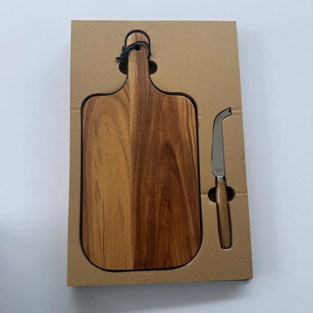 A wooden cheese board and a knife that is included in a champagne gift hamper.