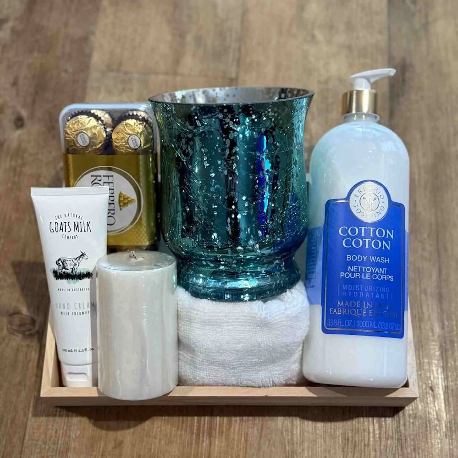 Luxury pamper gift hamper with Ferrero Rocher chocolates, goats milk hand cream, cotton body wash, candle, soft towel and glue glass candle holder.