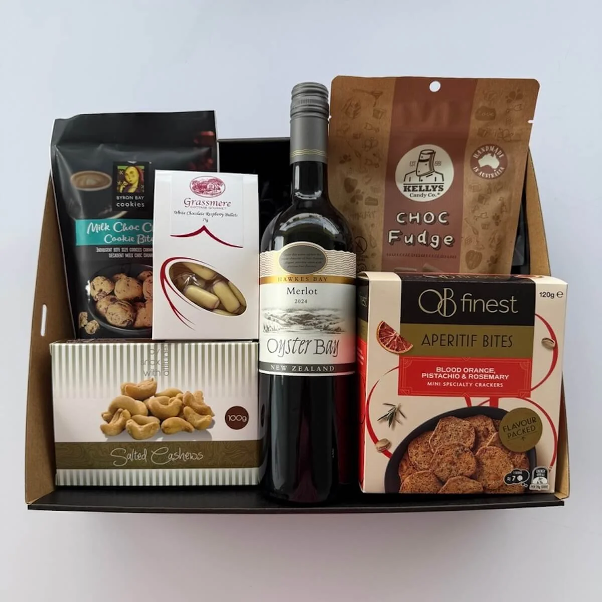 Gift hamper with 750 ml wine, chocolate fudge, cookies, cashew nuts, chocolate bullets and apretife bites.