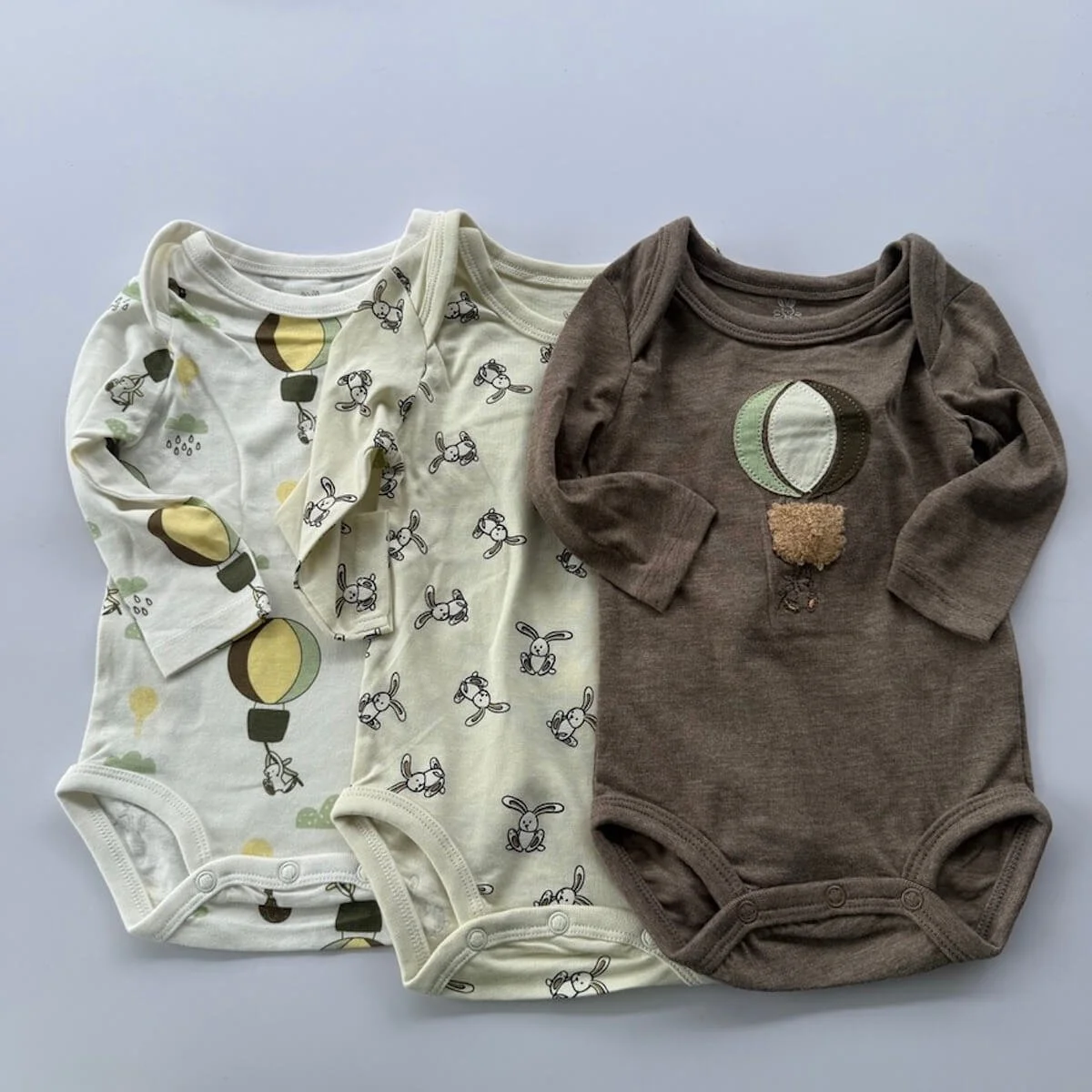 Three long sleeve legless baby bodysuits made from soft cotton, displayed together as part of a baby boy gift basket.