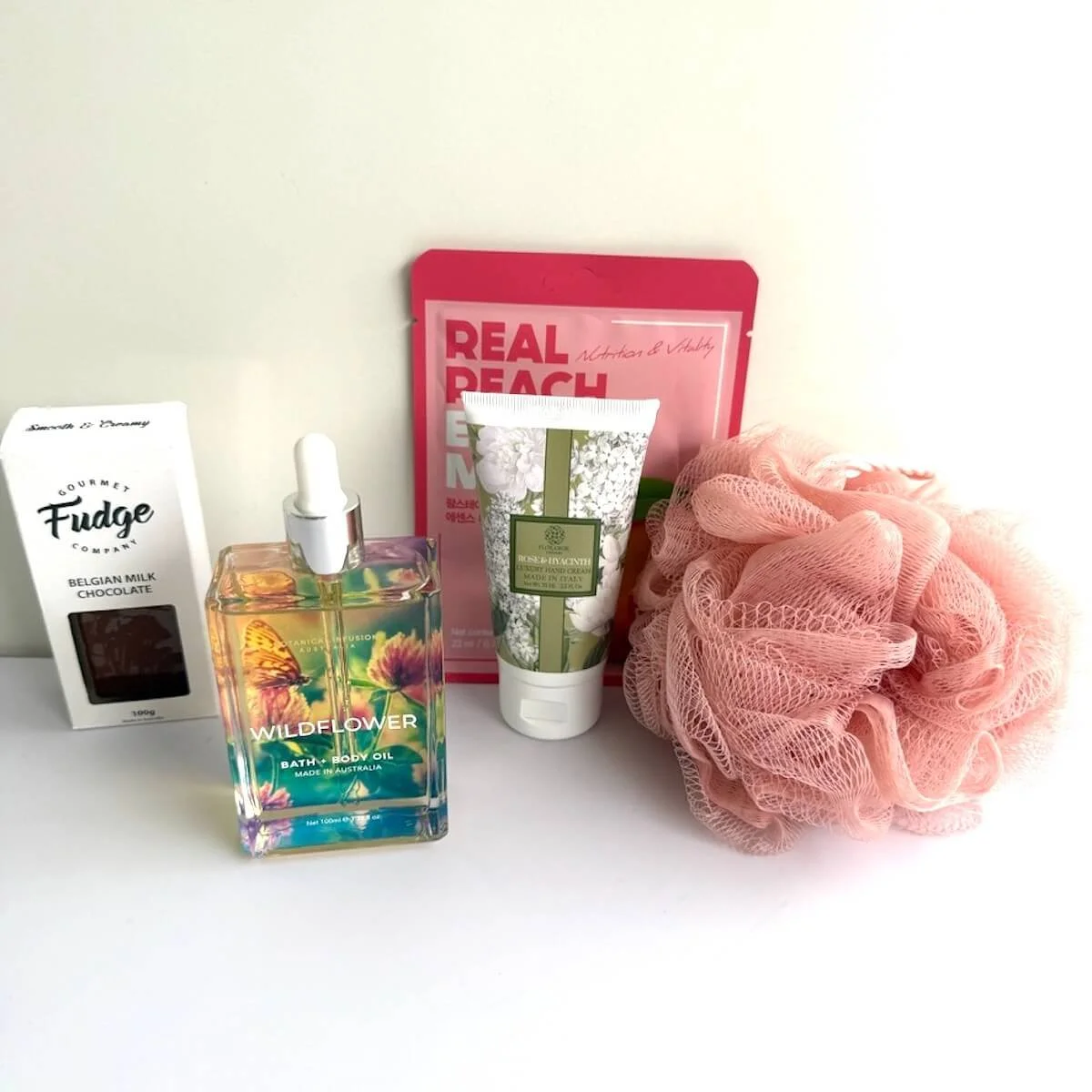 Luxury pamper gift items with Floramor hand cream, Wildflower bath oil, peach face mask, mesh body washer and gourmet chocolate fudge