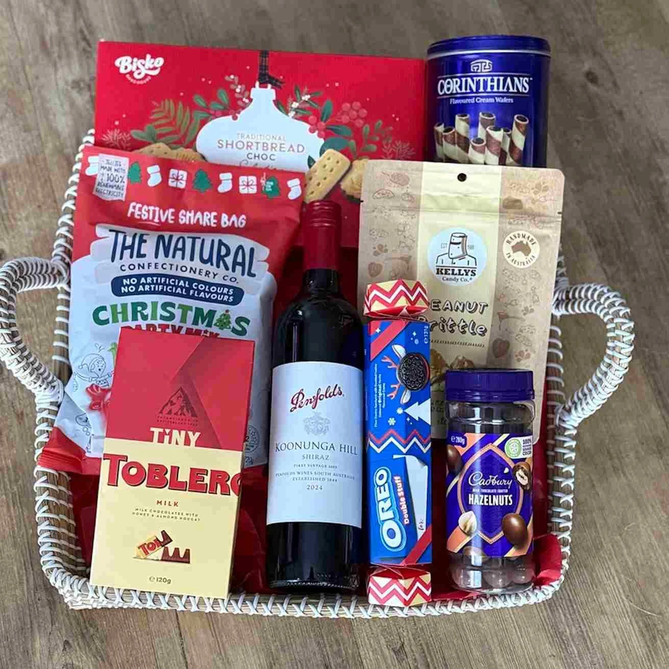 Large Christmas gift basket with wine, Bisko shortbread, Toblerone, chocolate-coated nuts, lollies, and Kelly's peanut brittle.