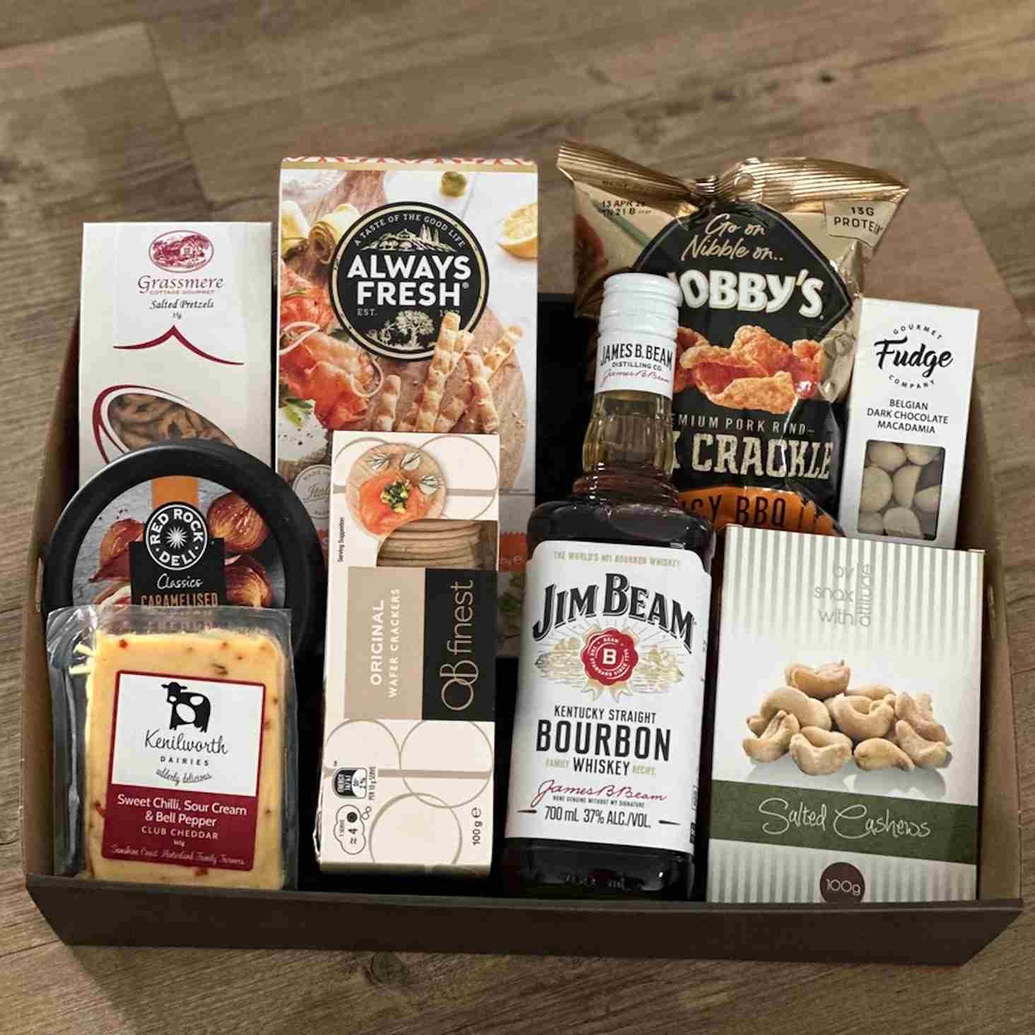 Gift hamper with bottle of spirits, cheese dip crackers grisinni fudge cashews & pork crackles.
