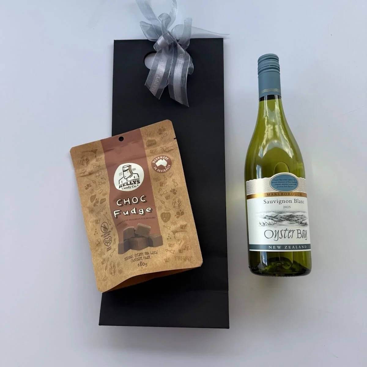 Black gift bag with a bottle of wine and Kelly’s chocolate fudge, an elegant wine and sweet treat gift perfect for celebrations and thank yous.