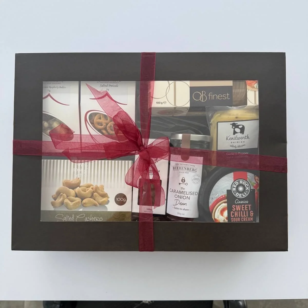 The Snax Gift hamper with a lid that includes gourmet Nuts, Pretzels, Fudge and Chutney with cheese, dip, crackers and chocolates.