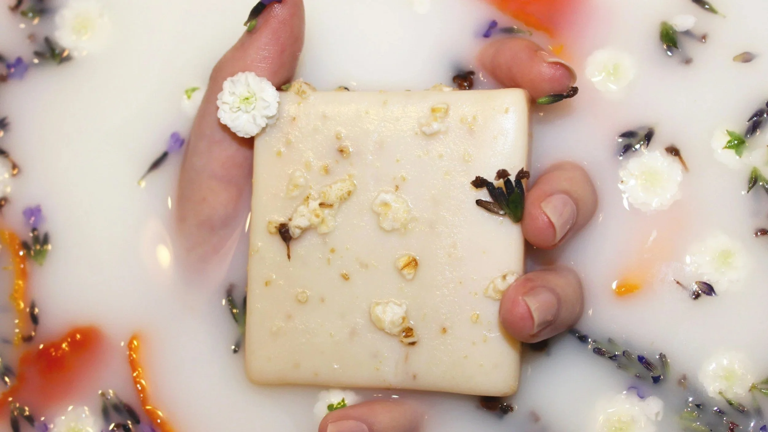 Hand holding a luxury soap with floating flowers, perfect for gifting on the Gold Coast
