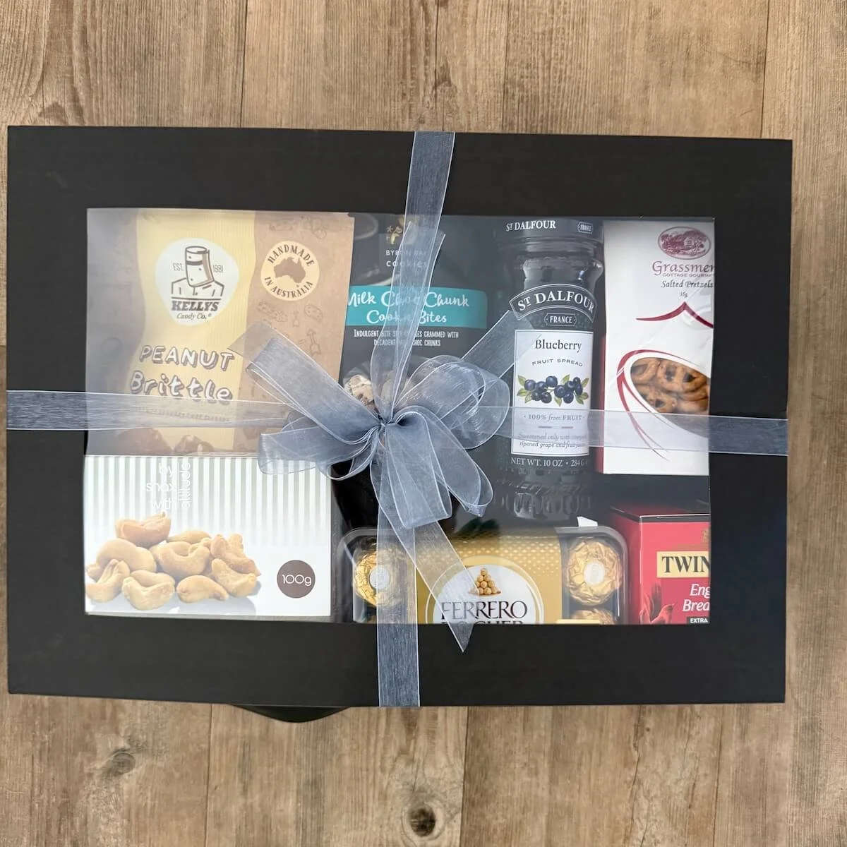 Ferrero Rocher gourmet gift box with lid on, tied with elegant ribbons in a black window gift box