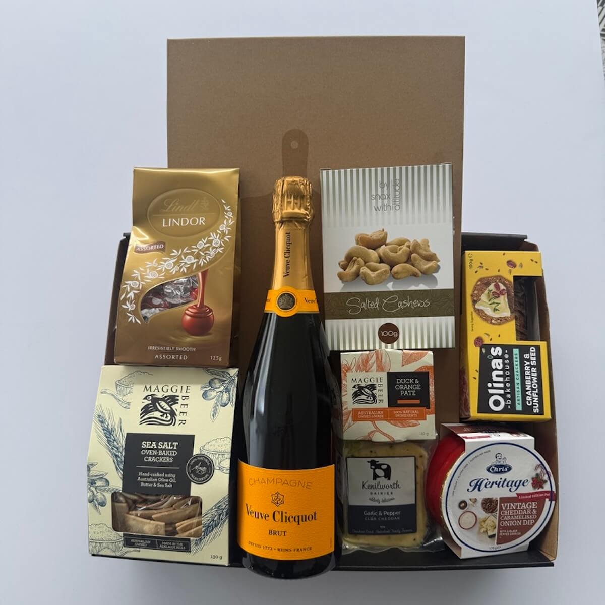 Veuve champagne gift hamper with a wooden cheese board and knife. Includes savoury a sweet items to create a stunning gift.