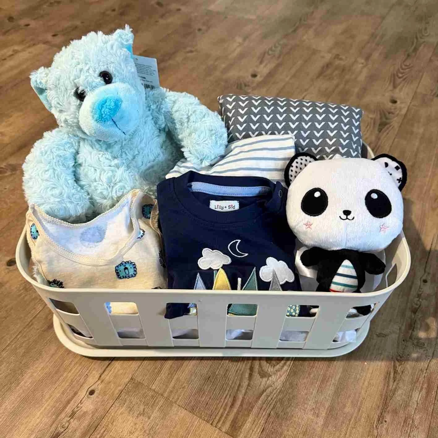 Baby boy gift hamper with blue teddy, baby outfit, singlet, pram toy and wrap arranged in a useful storage box.