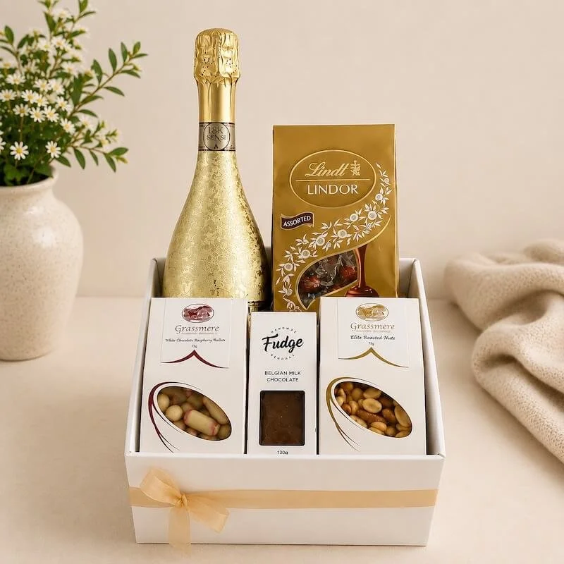 A gift box with a gold bottle of prosecco, lindt chocoaltes, raspberry bulletes, chocolate fudge and mixed nuts.