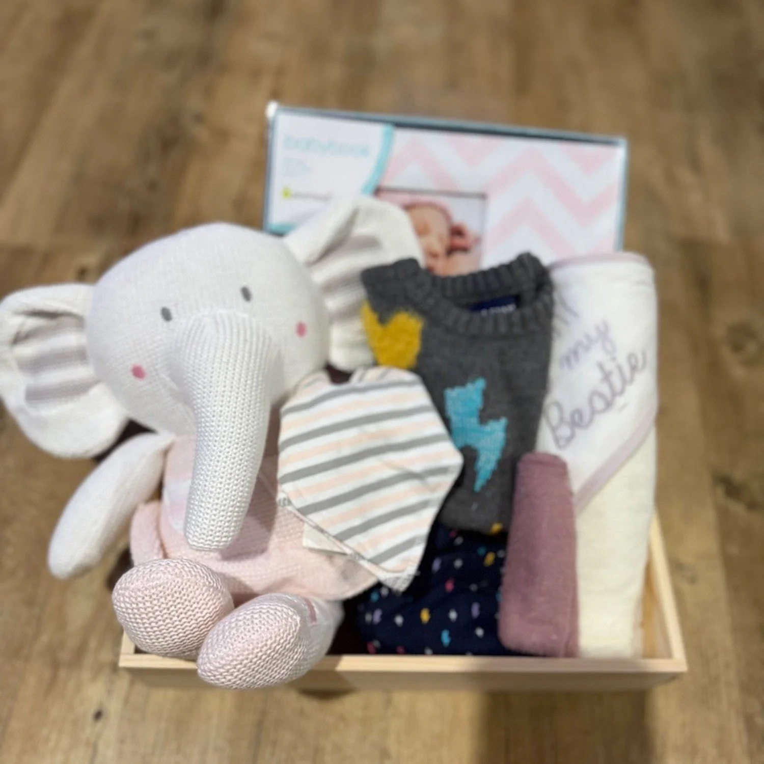 Jill Baby Hamper features a baby record book, hooded towel and washer, a 2-piece clothing set, soft knit baby toy and bib.