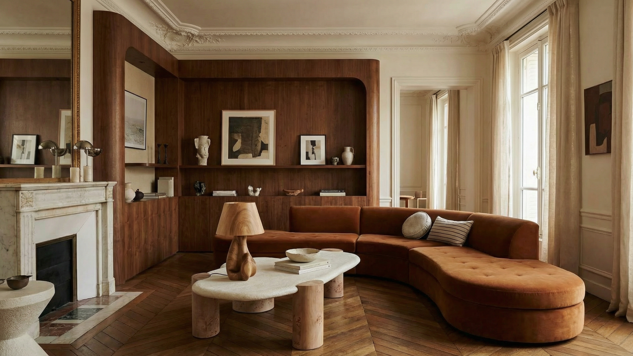 Living room with wooden wall panel, fireplace, sofa, coffee table, framed art, decorative vases, and curtains by large windows.