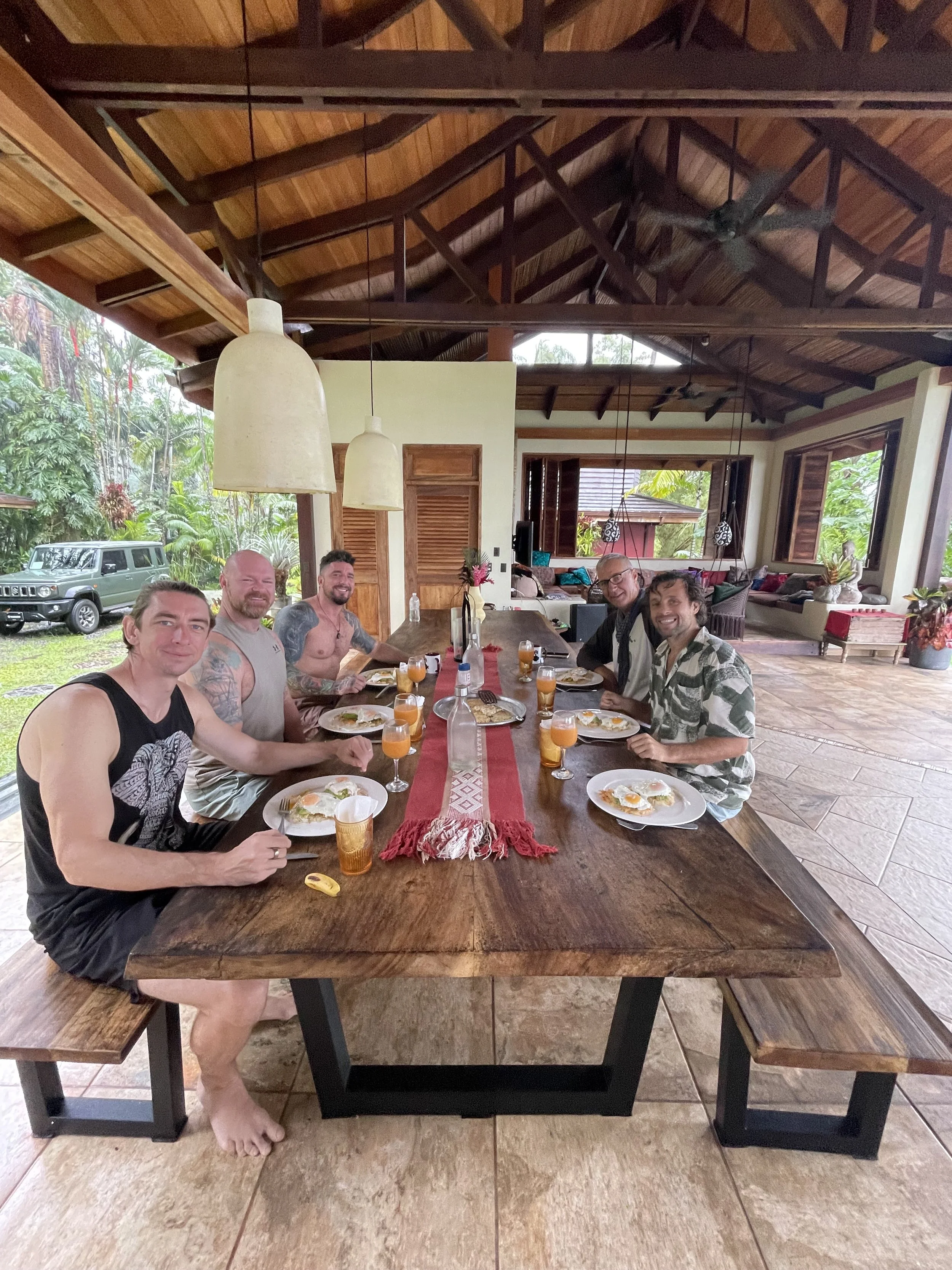 small group of men, sat at long wooden table, eating lunch at 5 day ayahuasca retreat