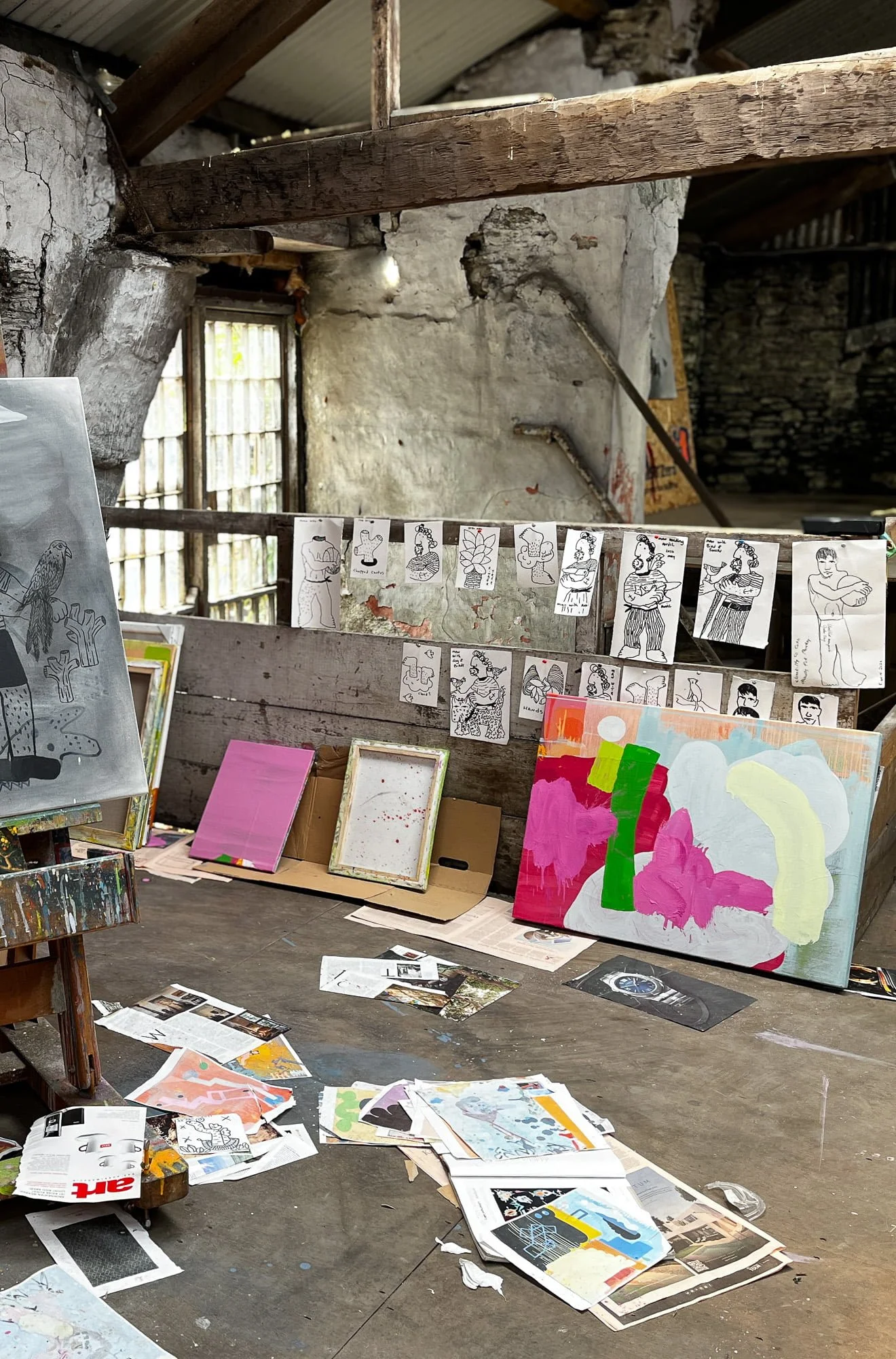 Abstract oil painting in progress among source material and drawings pinned to studio wall, pink green and blue forms developing, West Cork studio with scattered magazines and clippings on floor, Martin Finnin Irish artist