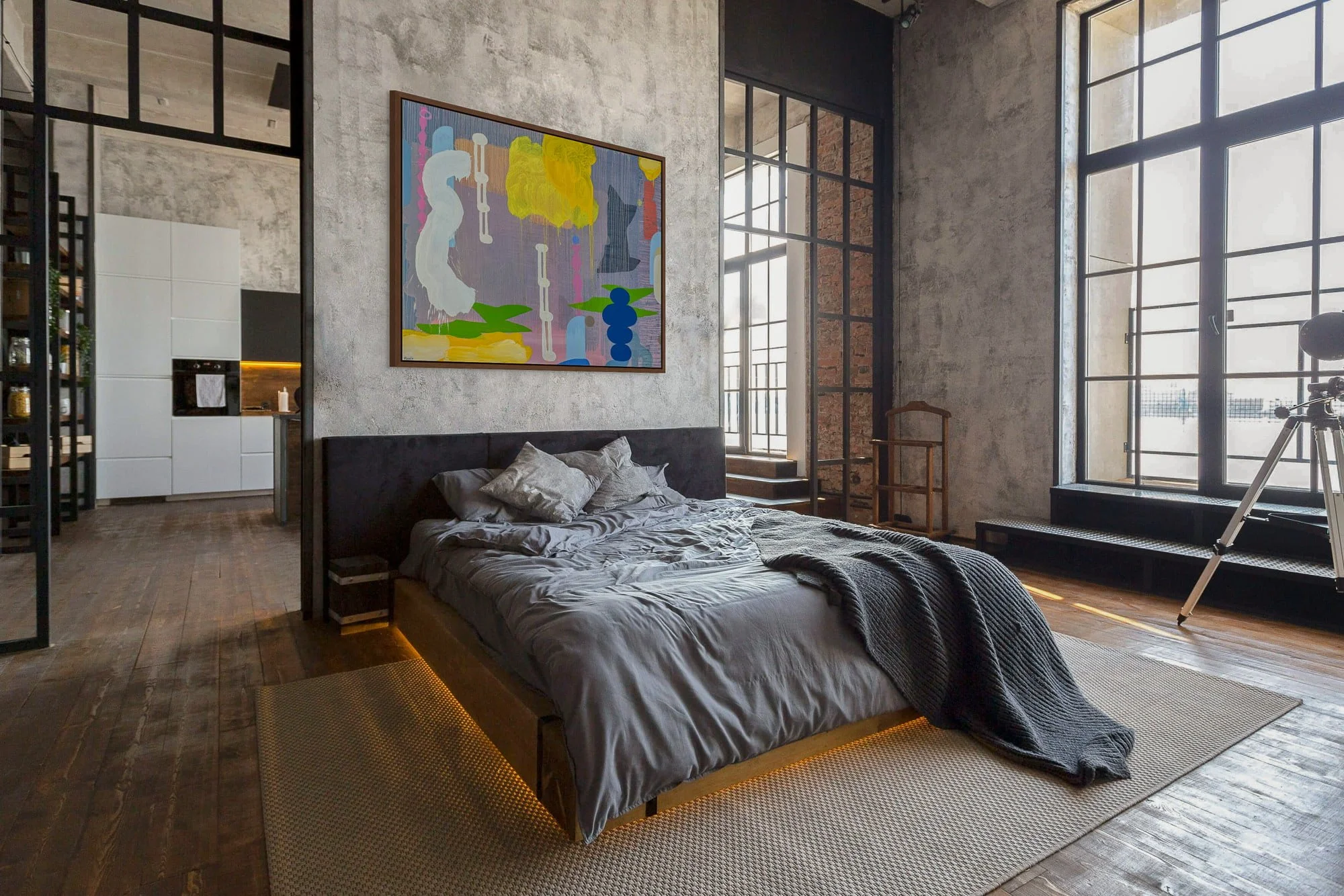 Large colourful abstract oil painting in moody industrial loft bedroom, yellow green blue and pink contemporary art on concrete wall, statement painting for dramatic urban interior, Martin Finnin Irish artist