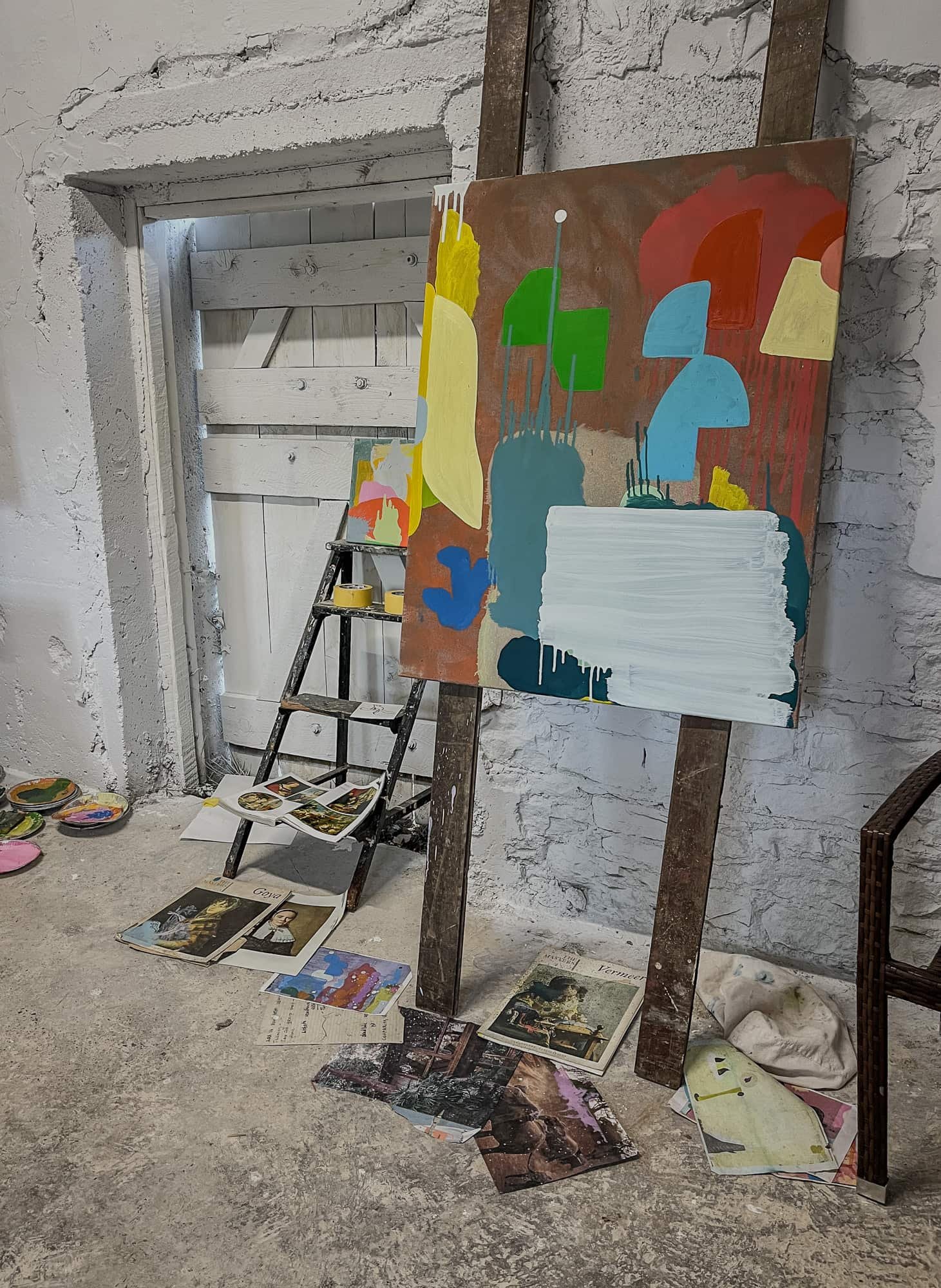 Abstract oil painting on easel in Ballyfin House studio, yellow green blue and red forms with white passage emerging, art books and source material on floor, Martin Finnin Irish artist