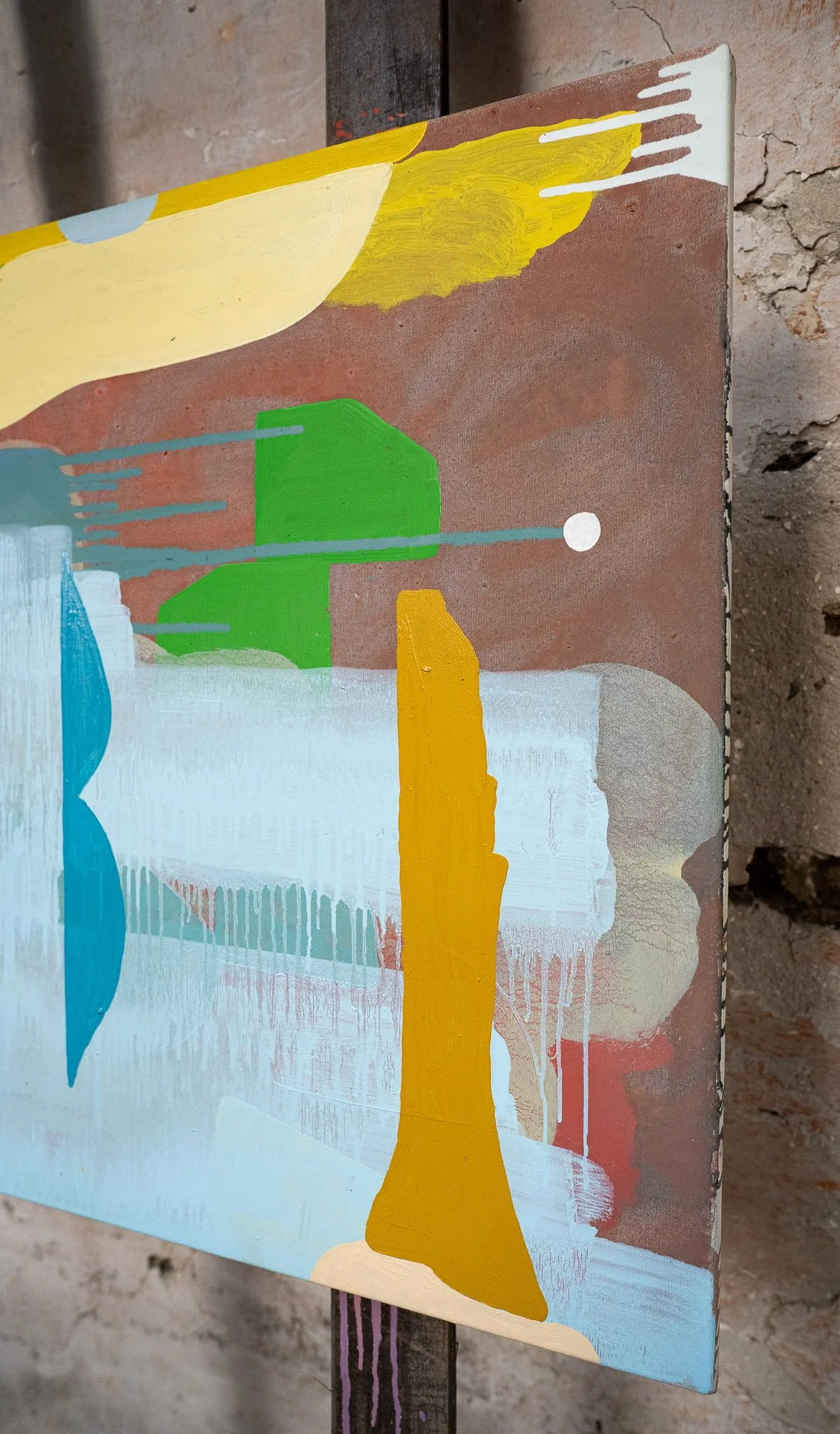 Canvas edge detail of original oil painting on easel, yellow ochre green blue and terracotta forms showing paint depth and texture, West Cork studio stone wall, Martin Finnin Irish artist