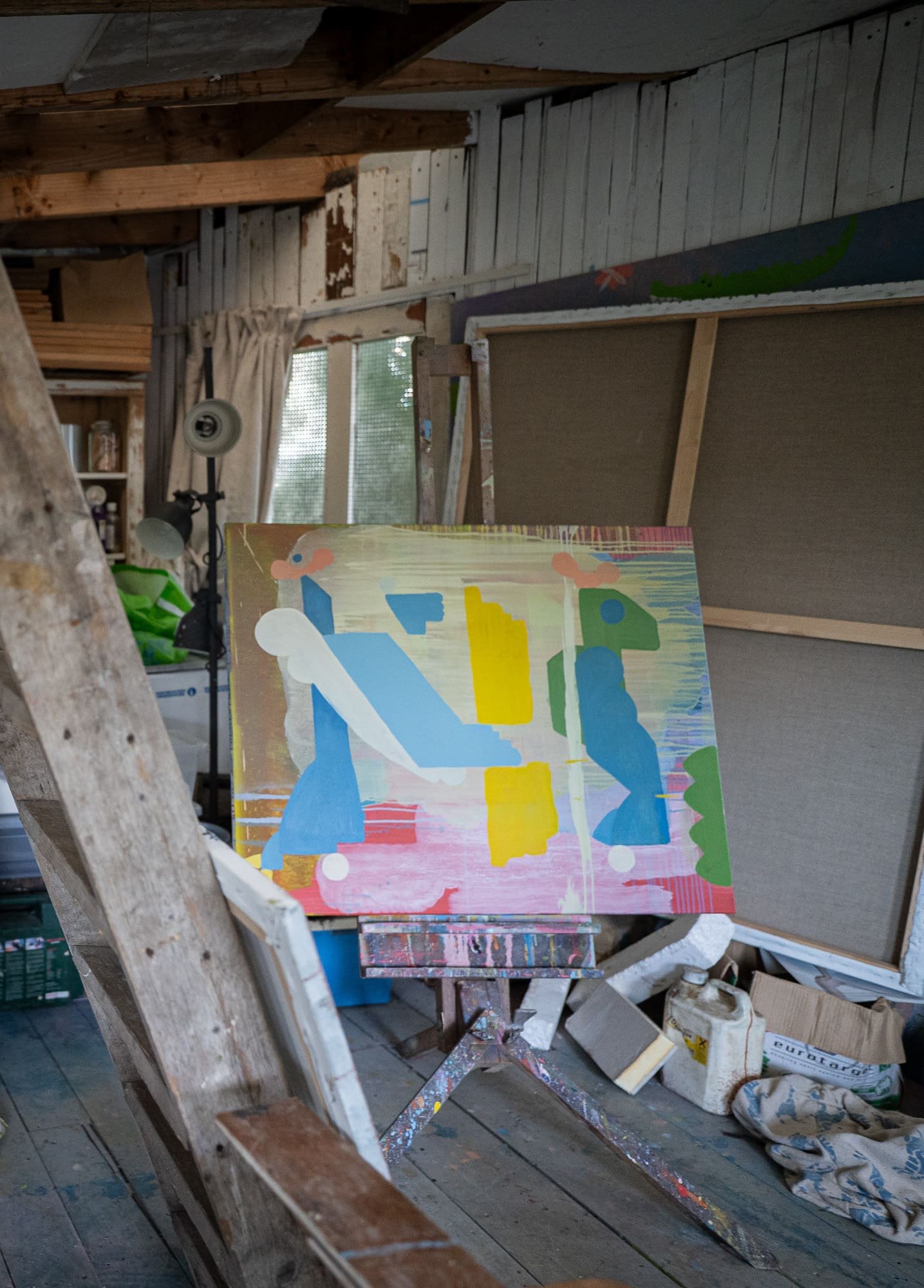 Abstract oil painting in progress on easel in West Cork studio, blue yellow green and pink forms emerging, working studio interior with canvases and materials, Martin Finnin Irish artist