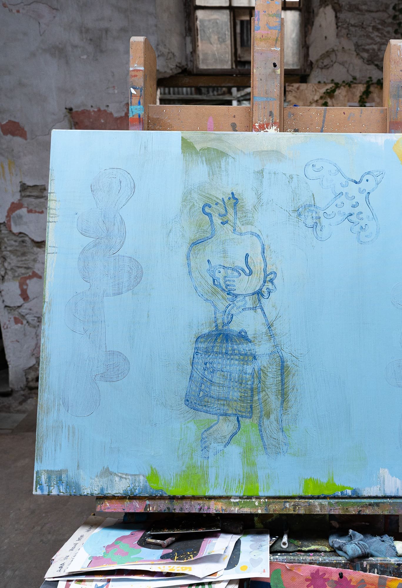Abstract oil painting in progress on easel in West Cork studio, blue canvas with figure holding birdcage, freed birds, early stage later painted over, Martin Finnin