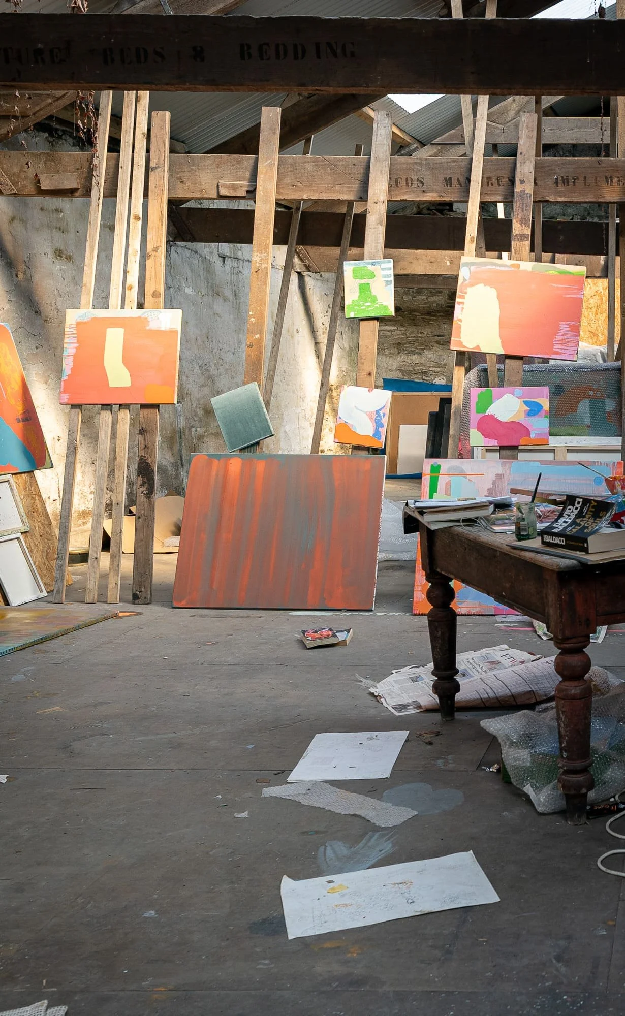 Early stage abstract oil canvas among multiple paintings in large West Cork studio, warm orange and terracotta ground, working studio atmosphere, Martin Finnin Irish artist