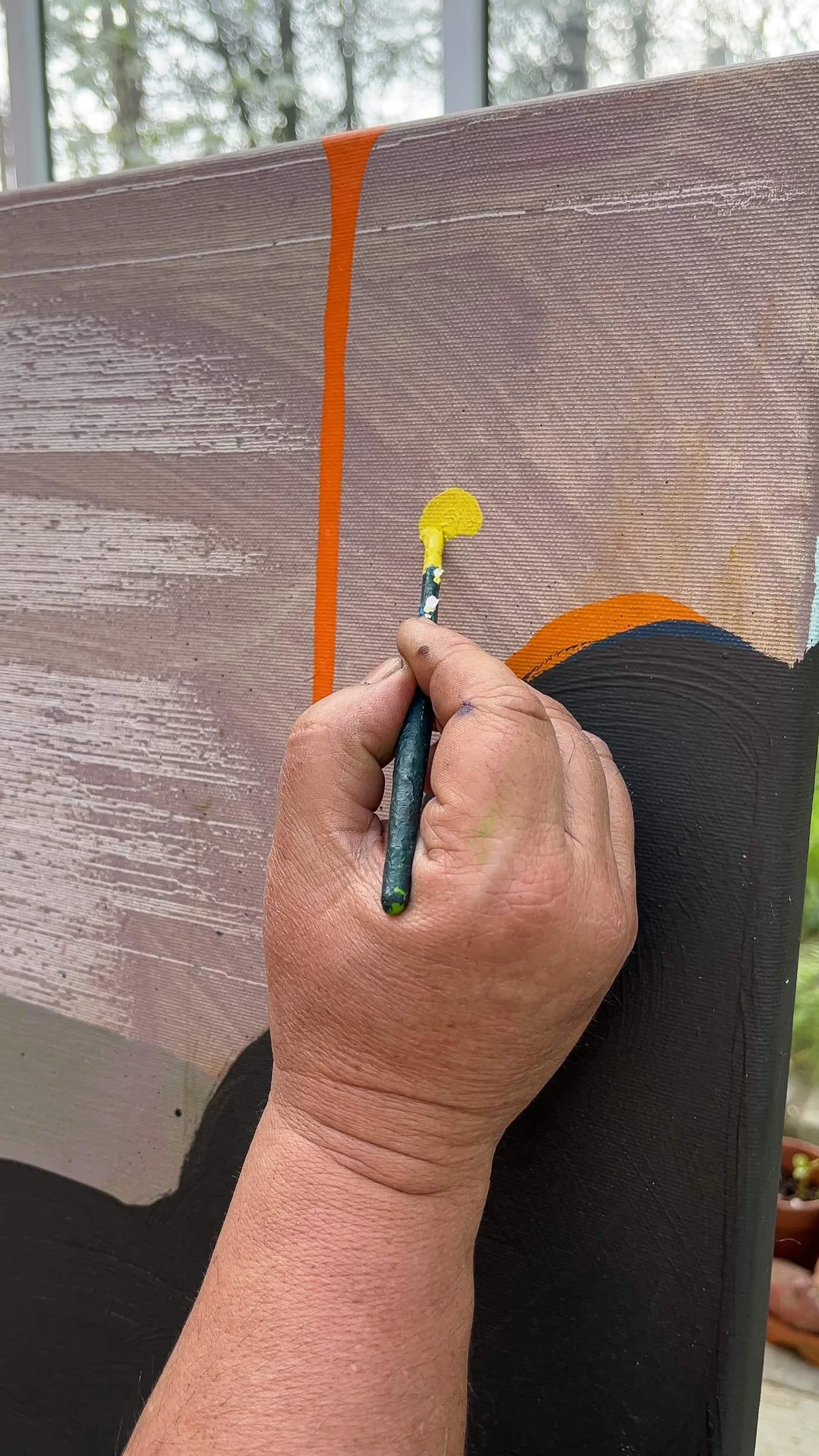 Close up of artist's hand painting small yellow dot onto abstract canvas, orange line and dark black form visible, precise detail work in West Cork studio, Martin Finnin Irish artist
