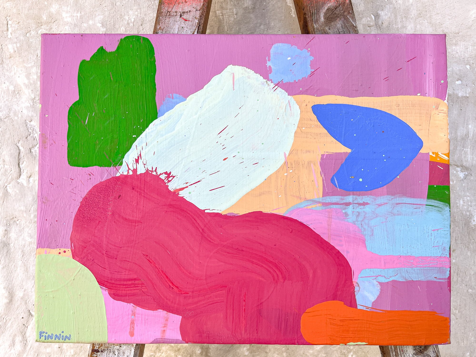 Small abstract oil painting on easel against stone wall, vivid pink crimson green blue and orange forms, West Cork studio, Martin Finnin Irish artist