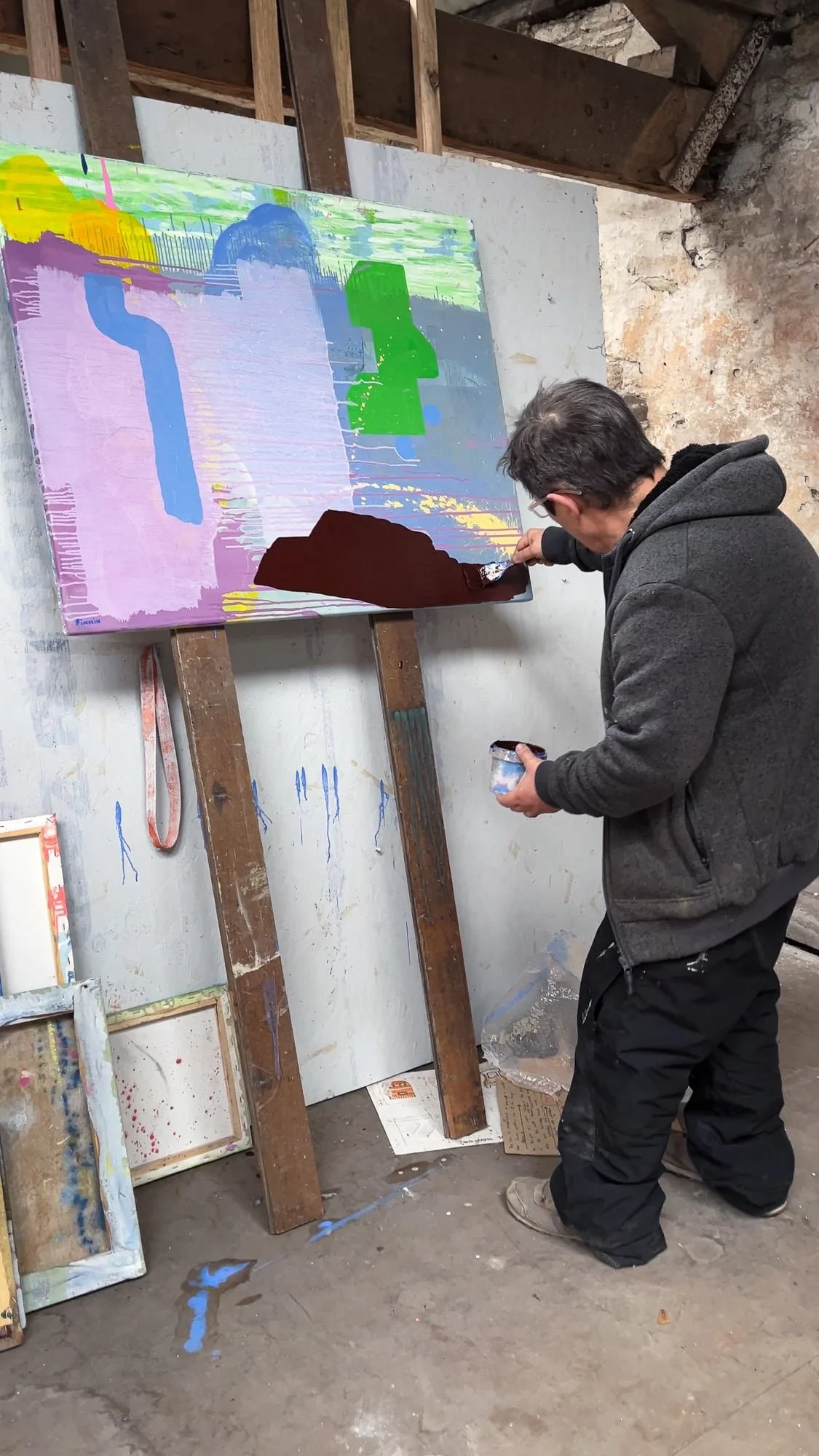 Irish artist Martin Finnin applying dark brown turf form to nearly finished abstract oil painting on easel, final stage of painting in West Cork studio, Martin Finnin Irish artist