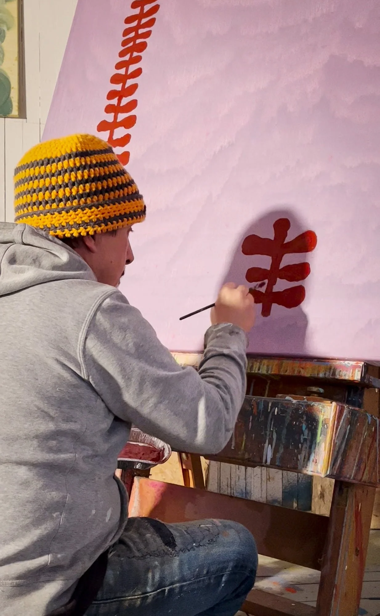 Irish artist painting red botanical form onto pale pink canvas, early stage of large abstract oil painting in West Cork studio, Martin Finnin Irish artist