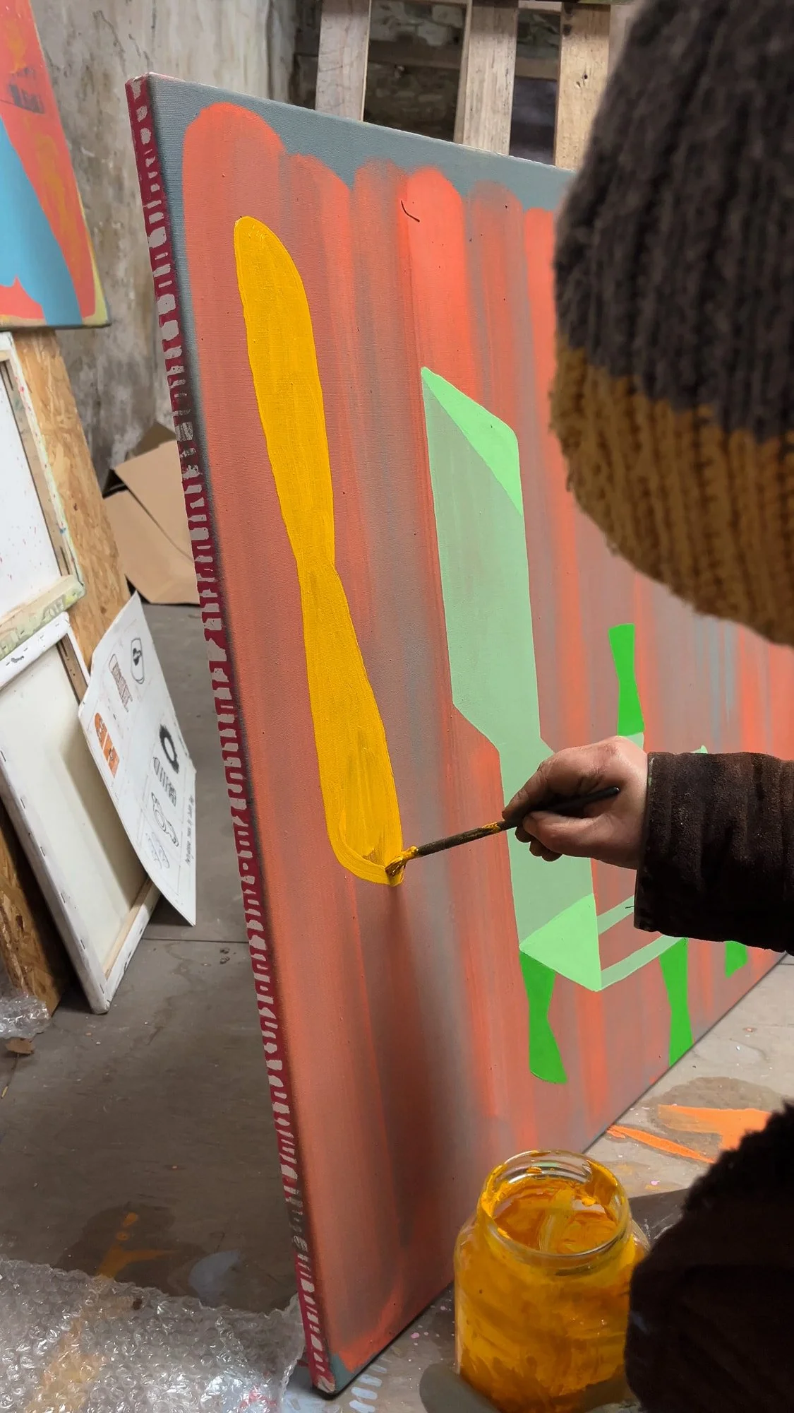 Artist painting yellow and green forms on terracotta orange canvas, abstract oil painting in progress in West Cork studio, Martin Finnin Irish artist