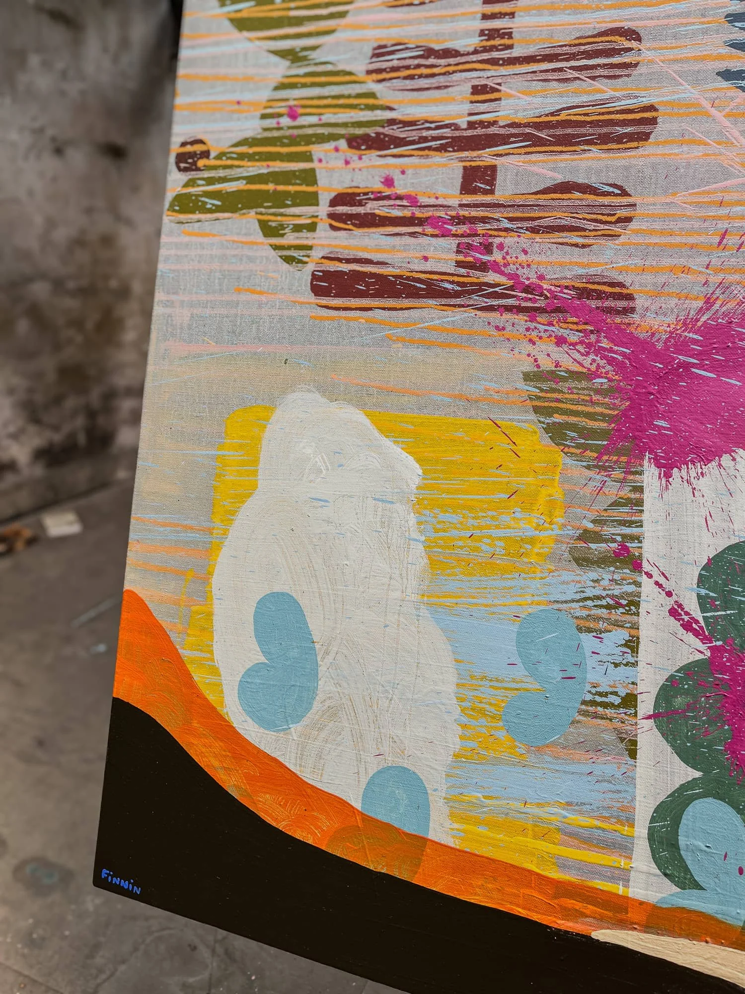 Close up of canvas corner showing orange black and white forms with magenta paint splatter, yellow olive and blue layered brushwork, Martin Finnin West Cork studio