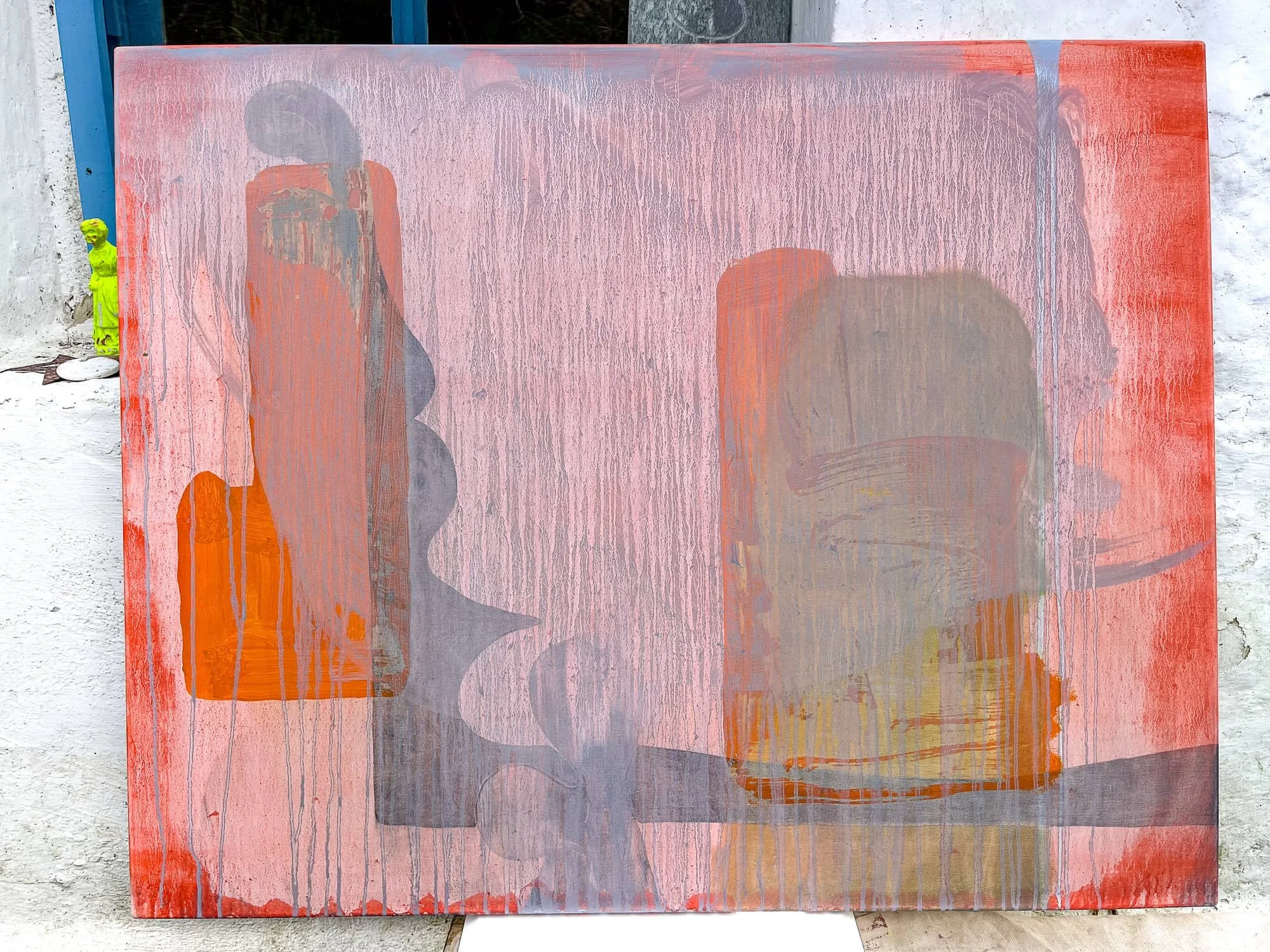Early stage abstract oil painting leaning against white wall in West Cork studio, coral pink and orange with grey wash over forms, painting in progress