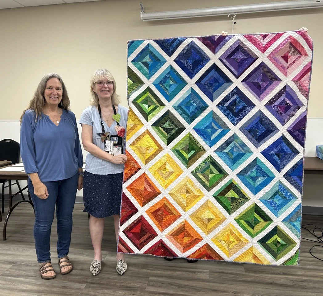 Vivian Bringslimark receives a thank-you quilt from Guild President Karen Moore in recognition of her extended term as Outreach Coordinator • Saturday, 5/23/26