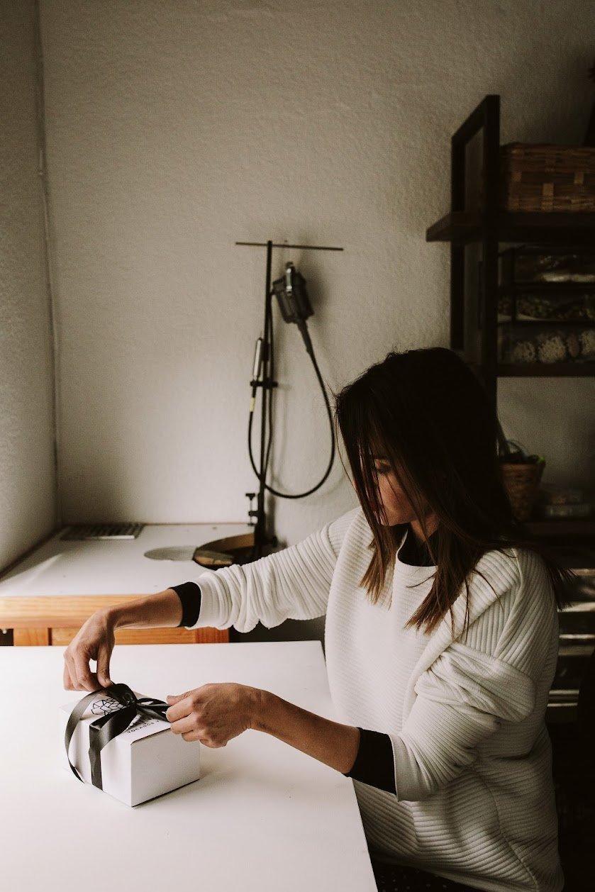 Person wrapping a gift at a white table.