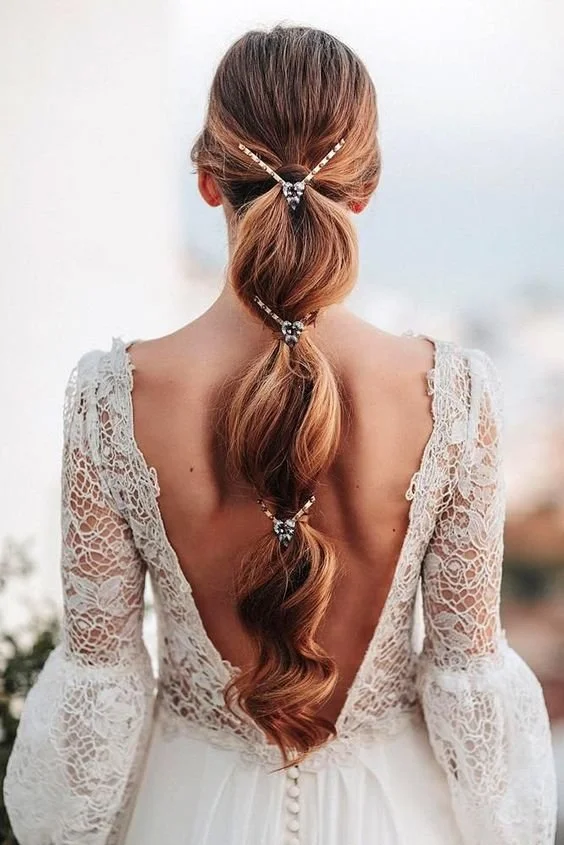 Rear view of a woman with an intricate ponytail and lace wedding dress