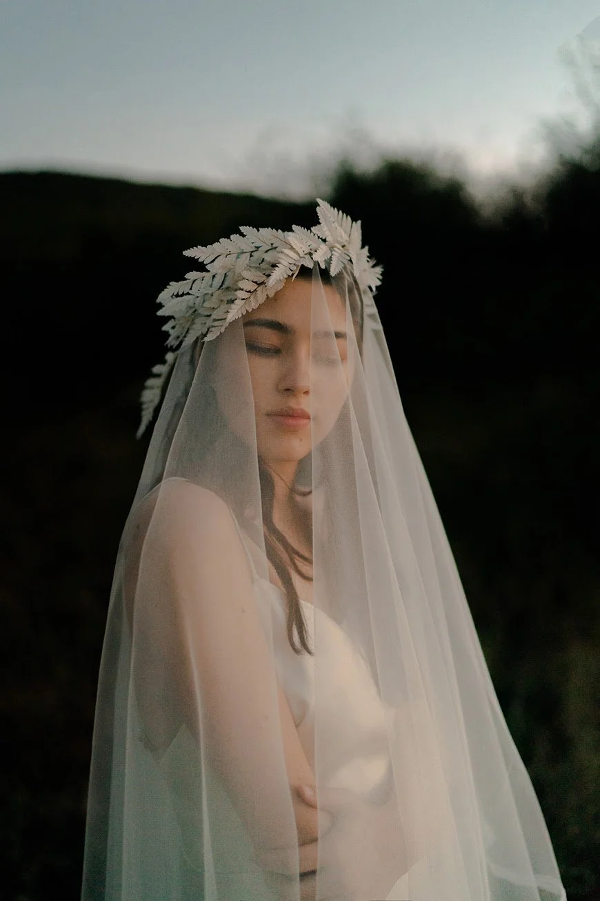 Woman wearing a wedding veil and floral headpiece outdoors