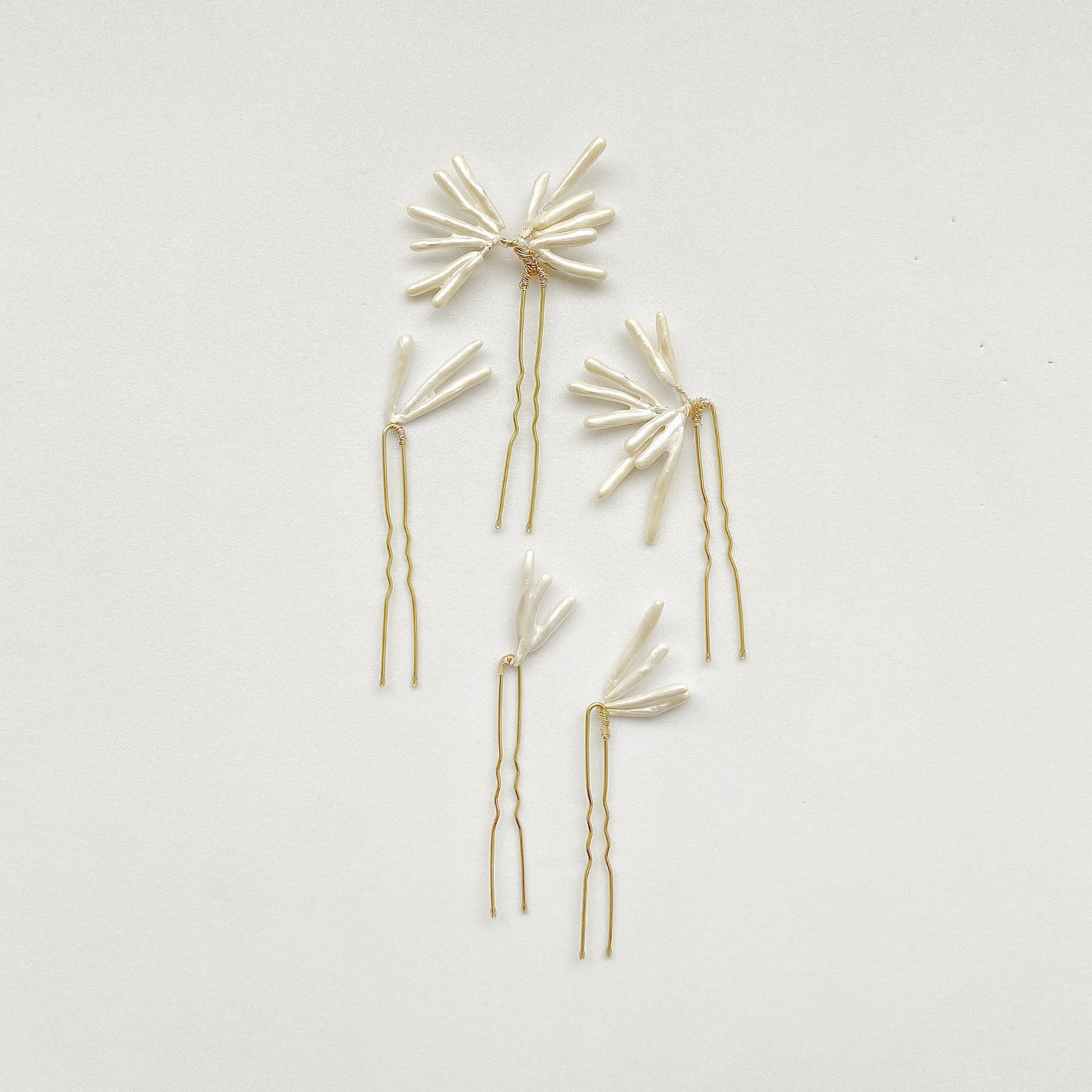 Decorative hairpins with white floral designs on a light background