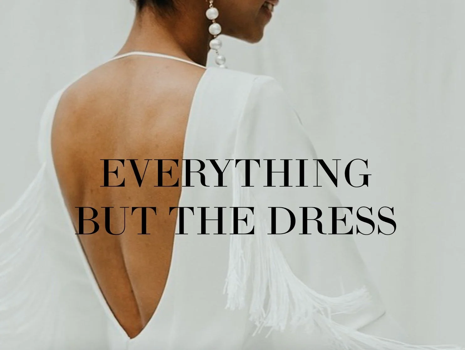Woman in white dress with open back, pearl earrings, text reads 'Everything But The Dress'