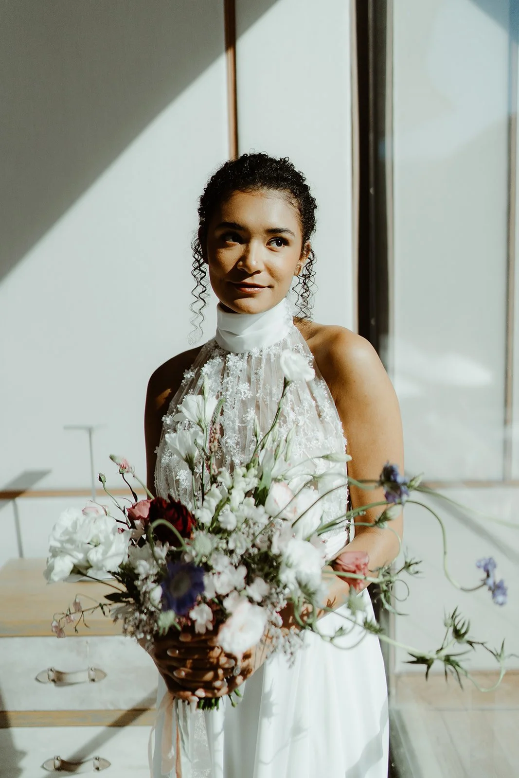 Woman in a white dress holding a bouquet of flowers indoors