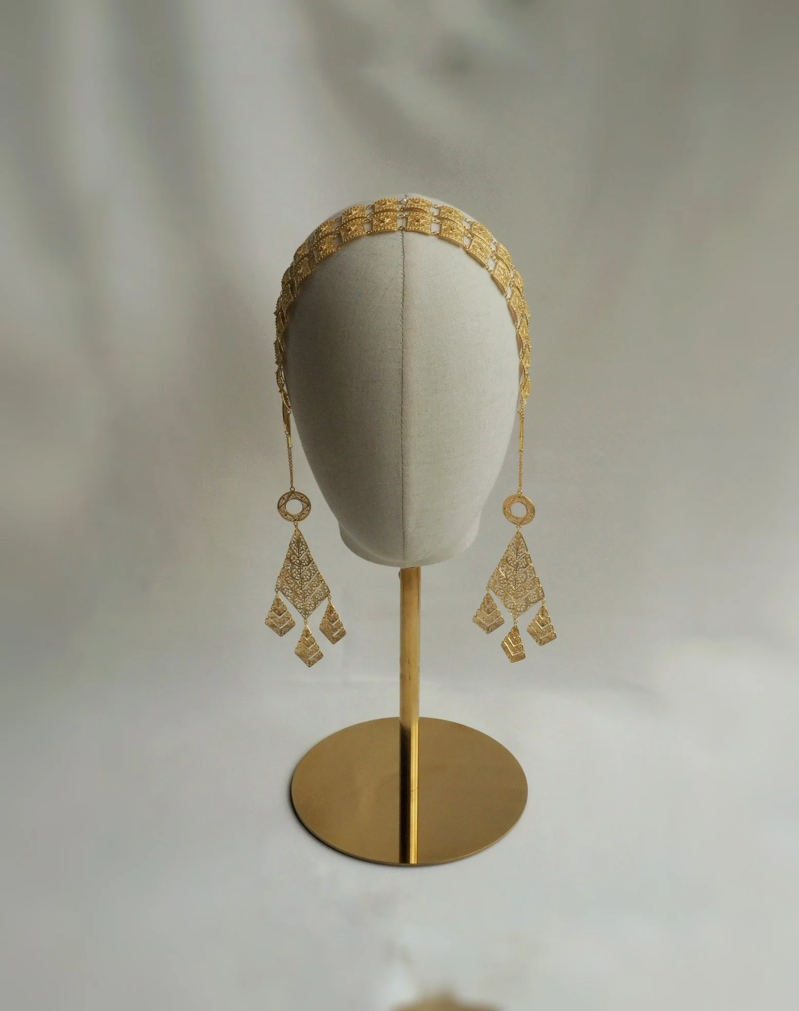 Gold headpiece on a mannequin with intricate hanging ornaments.