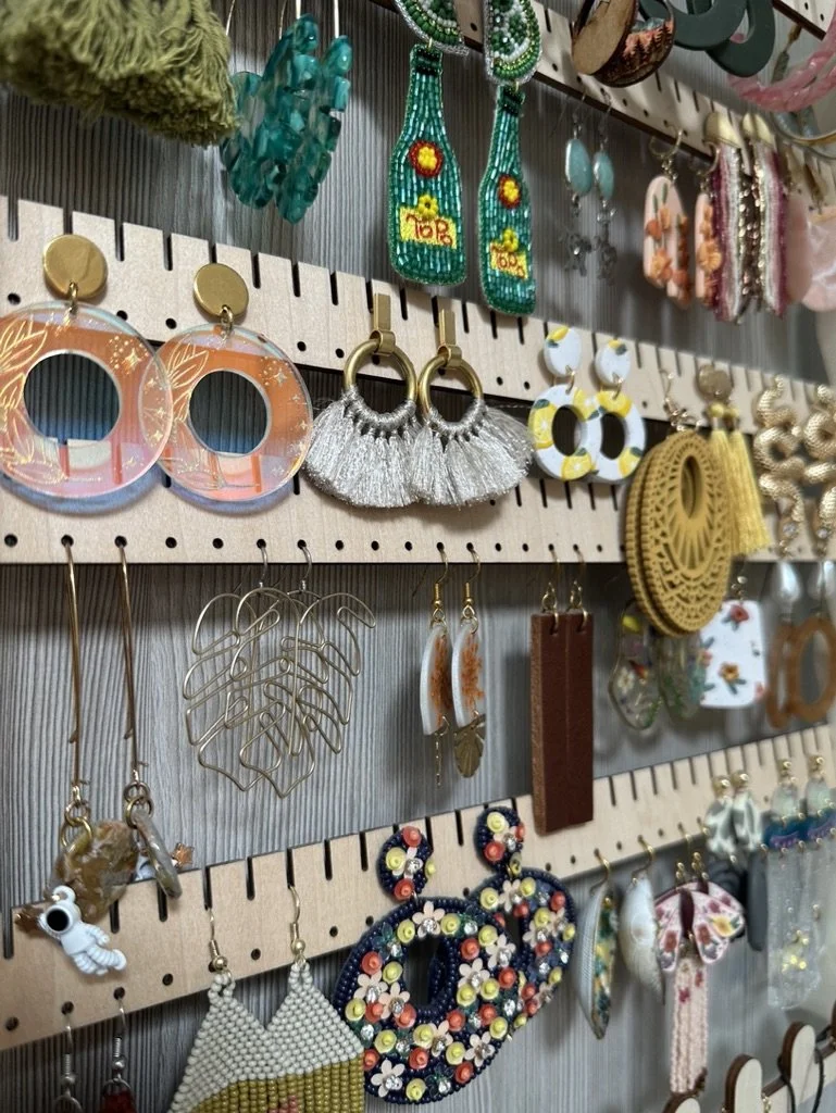 Assorted earrings displayed on a wooden pegboard