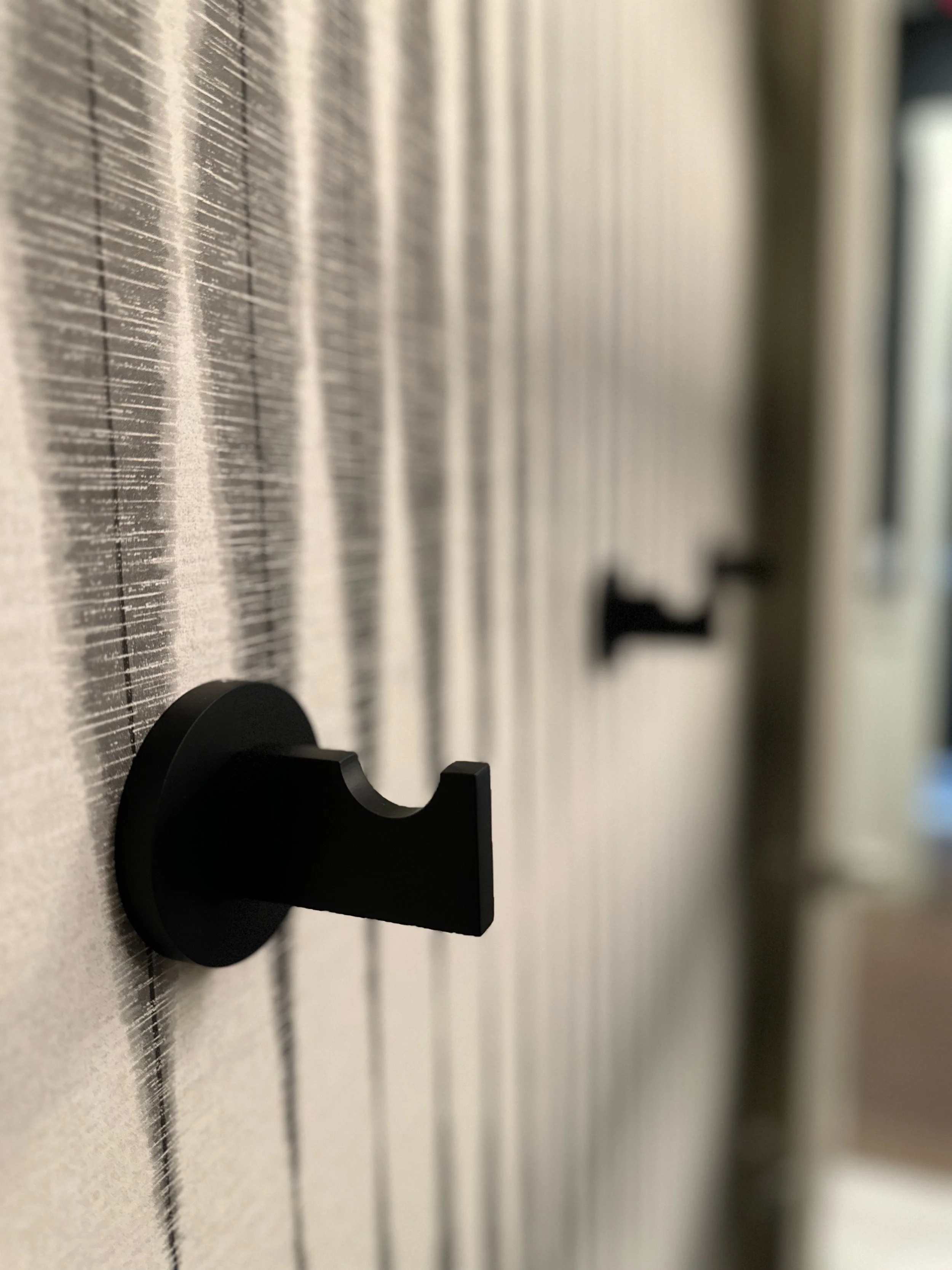 Black wall hooks on a patterned wallpaper background