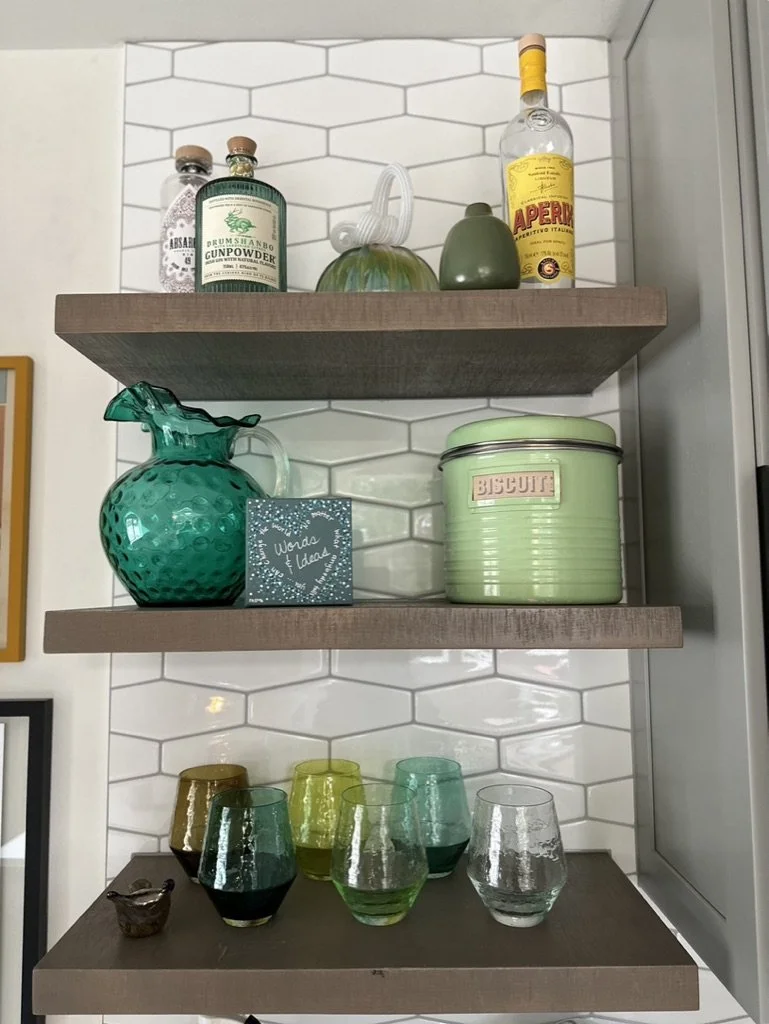 Kitchen shelves with bottles, glassware, and decorative items.