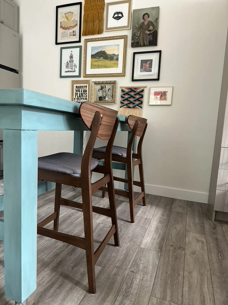 Interior with turquoise table, wooden chairs, and art-filled gallery wall.